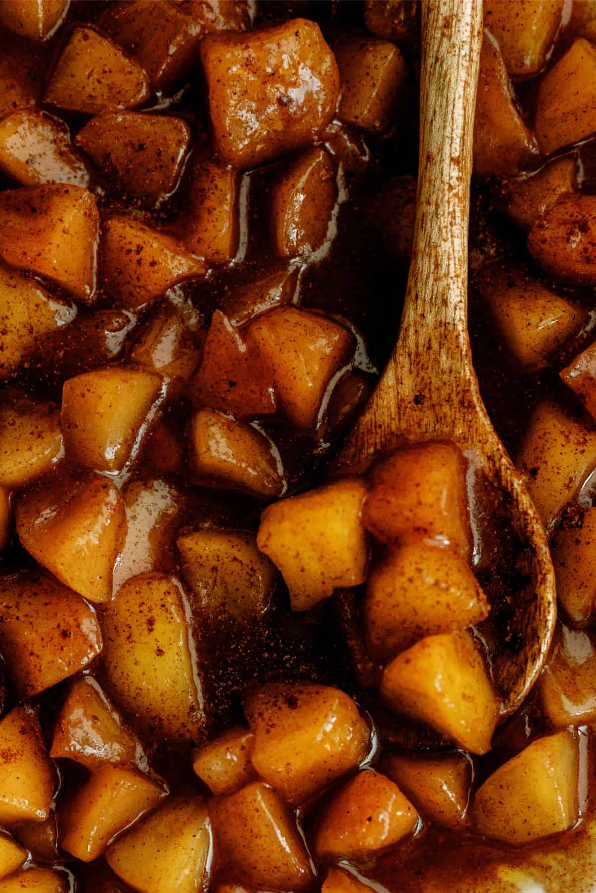 Close up of Copycat Cracker Barrel Cinnamon Apples (in the Slow Cooker) with a wooden spoon.
