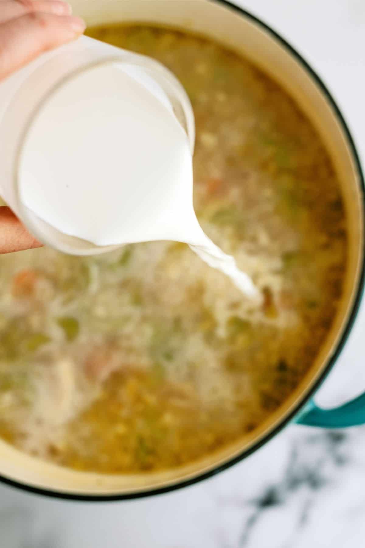 Pouring half and half from a measuring cup into the stock pot.