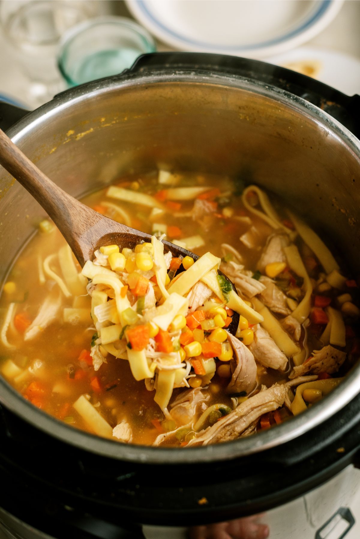 Instant Pot Chicken Noodle Soup in the instant pot with a wooden spoon lifting a serving out