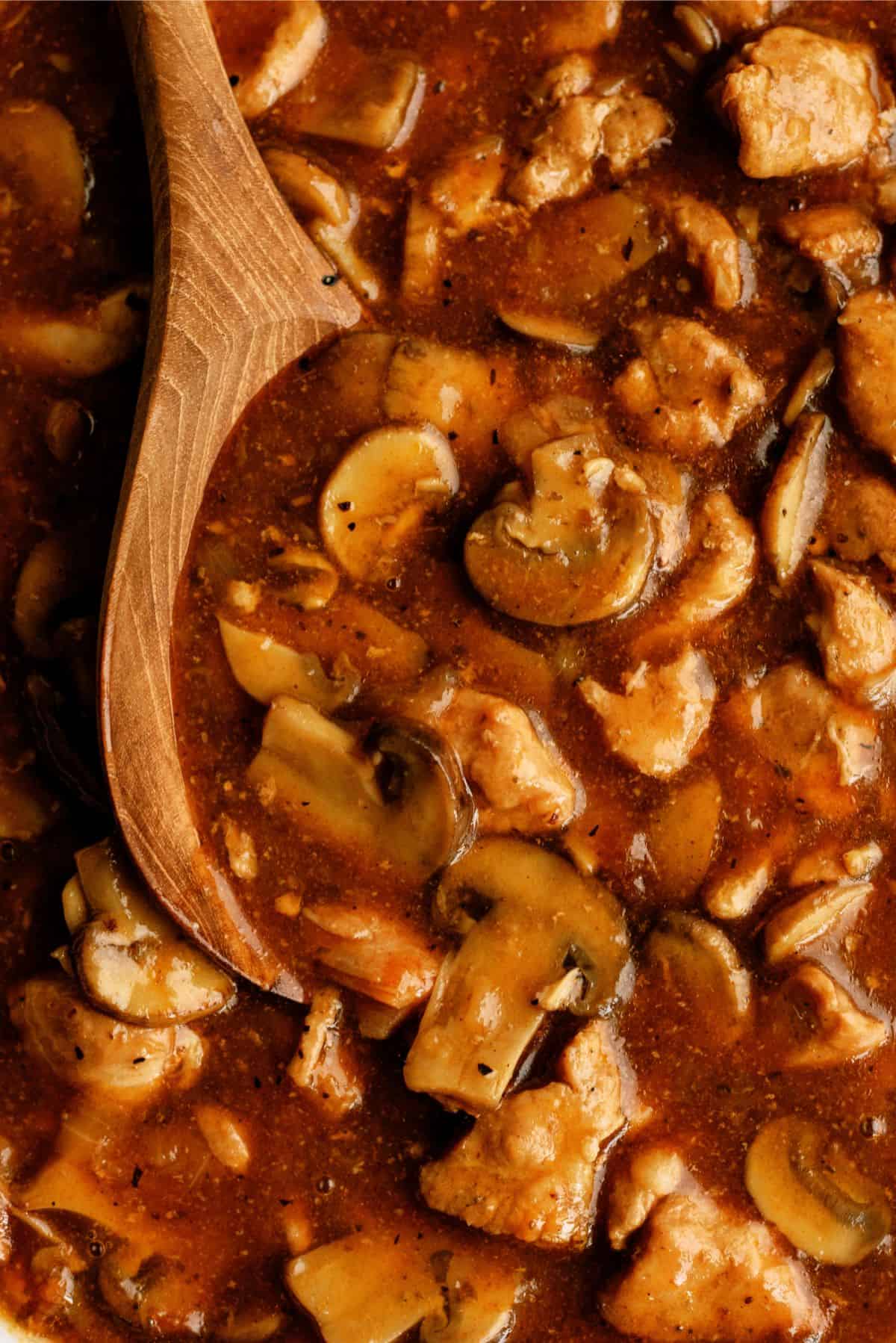 Close up of Instant Pot Pork Tips and Gravy with a wooden spoon