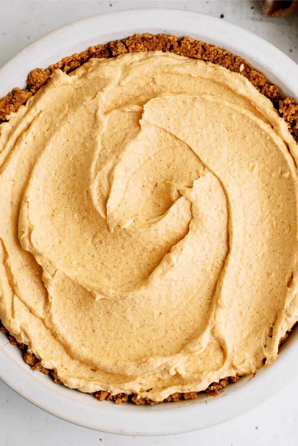 A close-up view of a pie with a smooth, creamy filling and a crumbly crust.