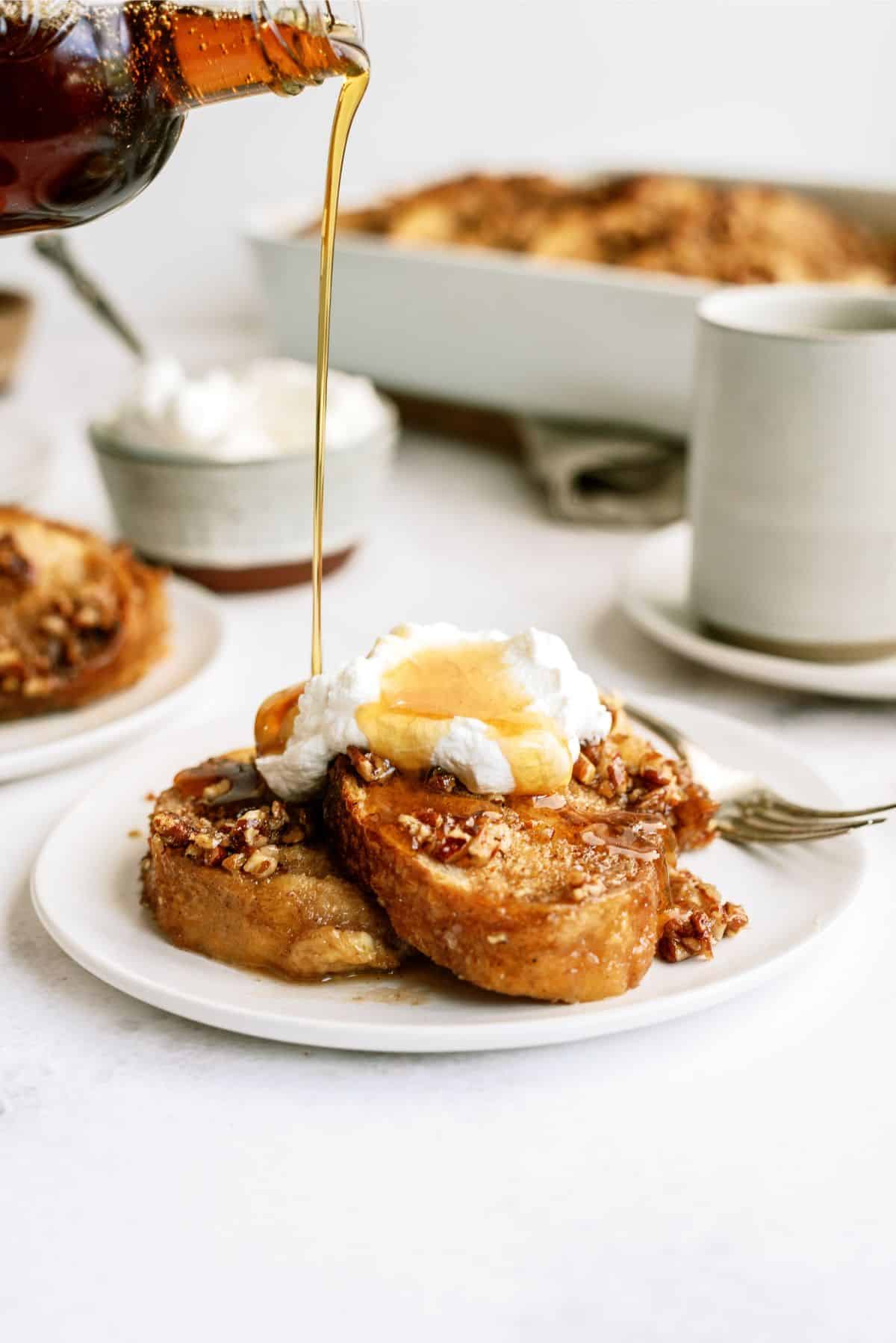 pouring maple syrup on top of a plate of Overnight Praline Pecan French Toast Bake