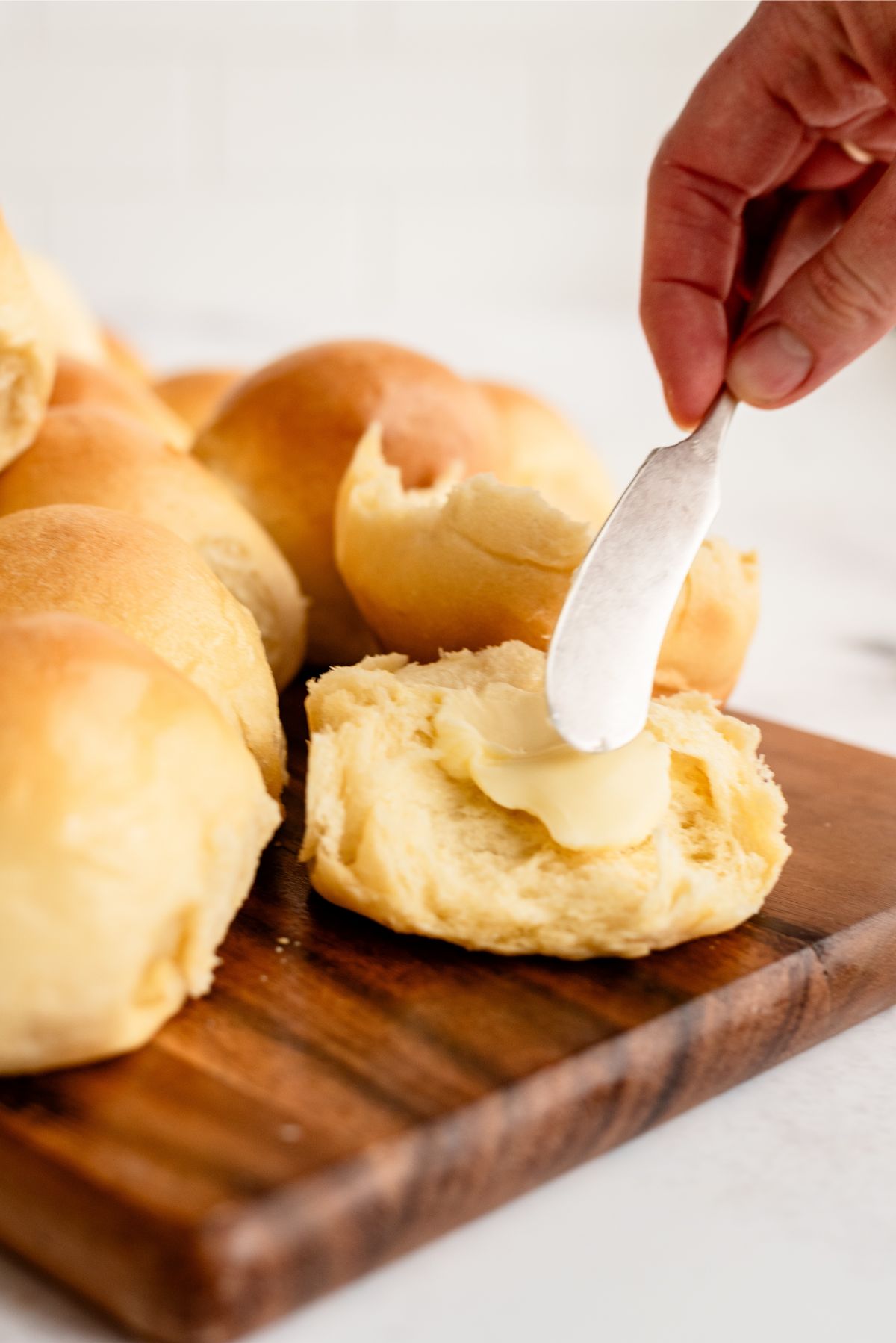 Spreading butter on a Parkerhouse Rolls