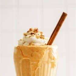 Pumpkin Pie Milkshakes topped with whip cream and a cinnamon stick.