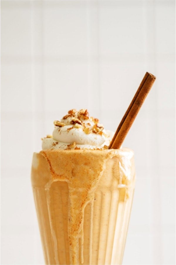 Pumpkin Pie Milkshakes topped with whip cream and a cinnamon stick.