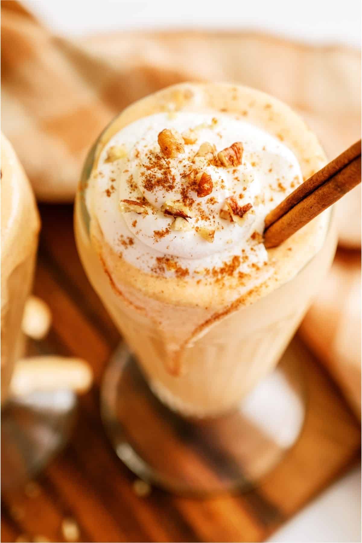 Top view of a Pumpkin Pie Milkshake topped with whip cream and cinnamon sticks.