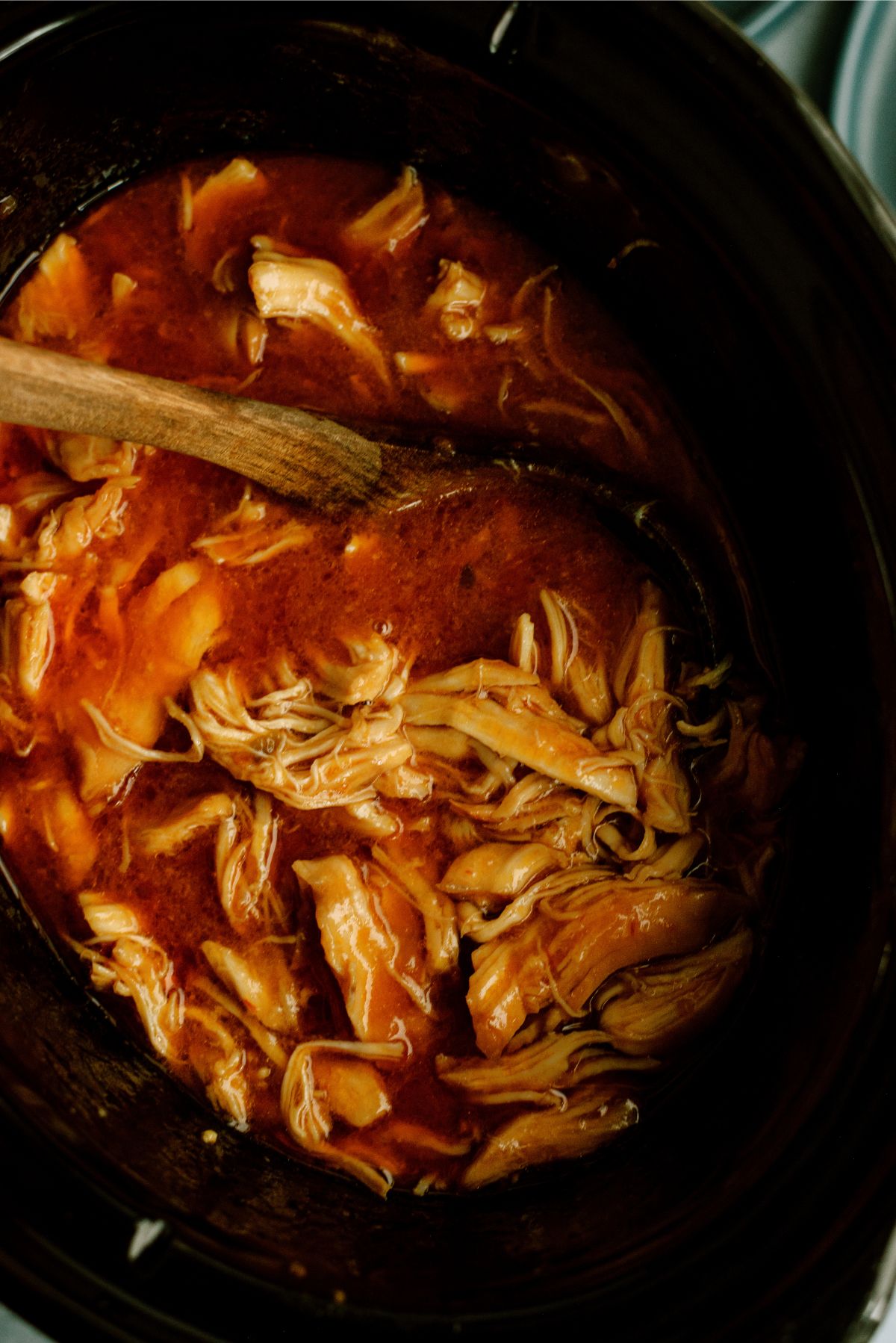 Slow Cooker Apricot Chicken in the slow cooker with a wooden spoon