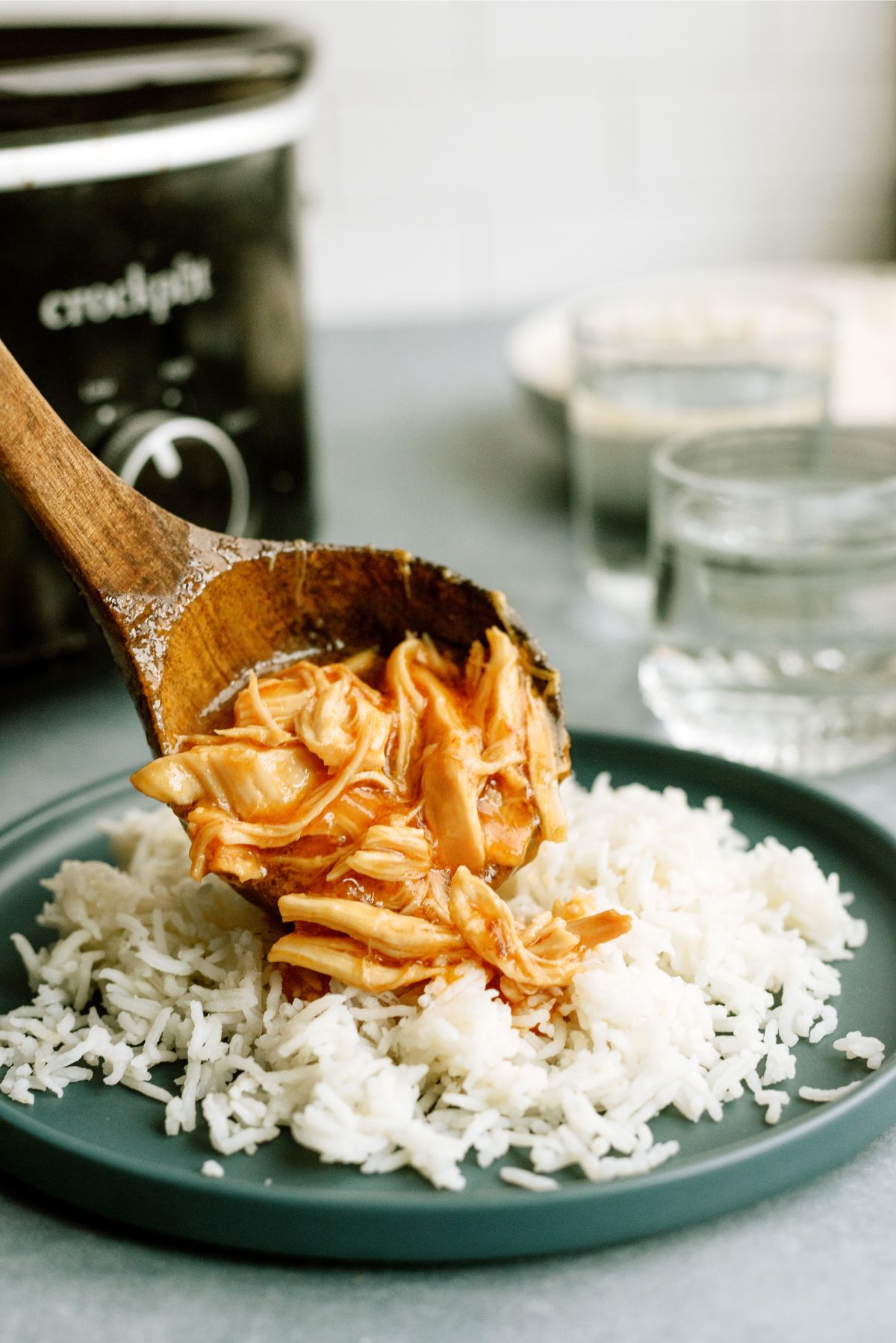 A scoop of Slow Cooker Apricot Chicken from the slow cooker placed on top of a plate of rice