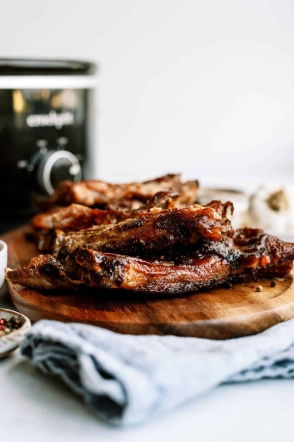 St. Louis Slow Cooker Ribs on a cutting board with the slow cooker in the background.