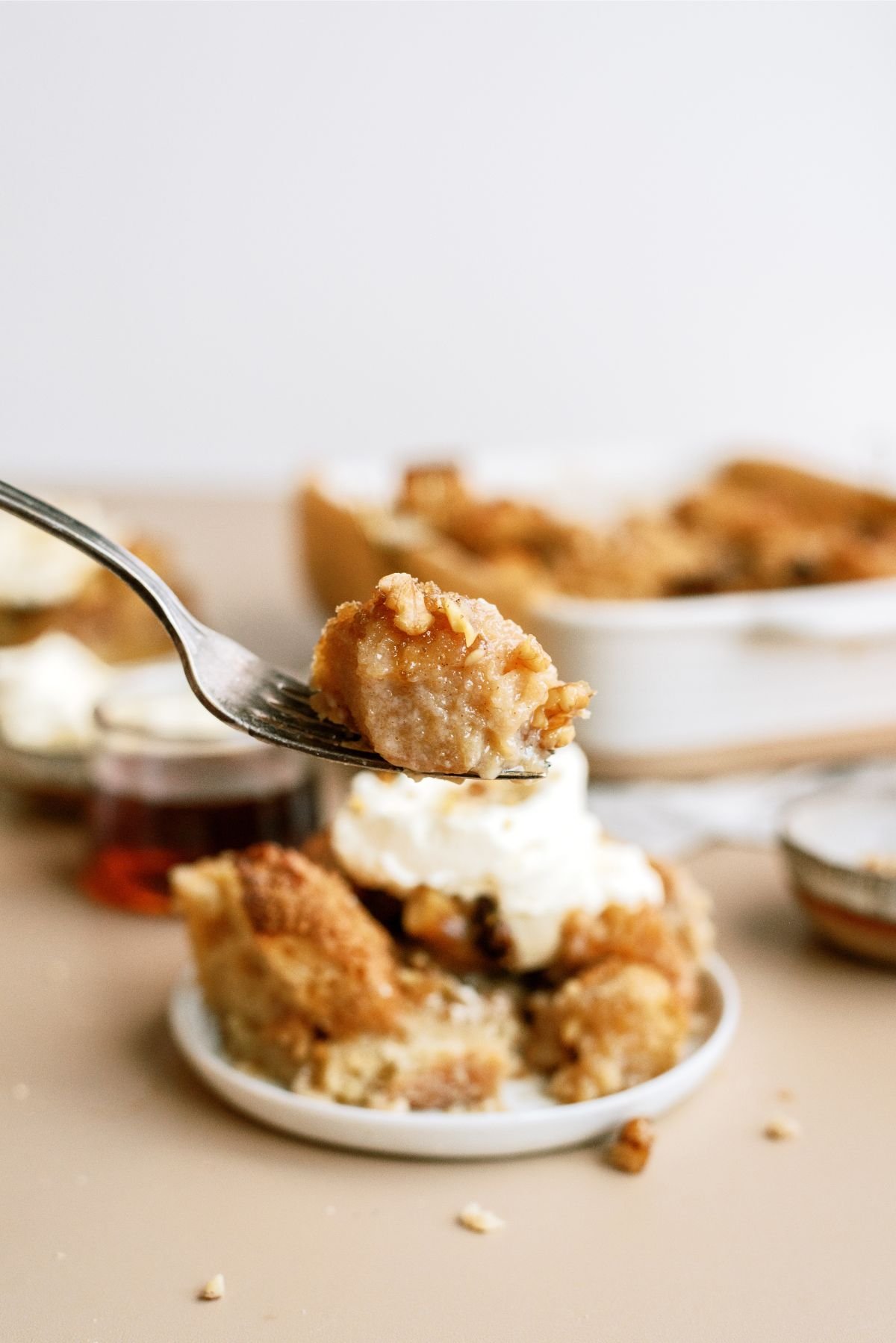 A serving of Brown Sugar and Maple Bread Pudding on a plate with a fork holding up a bite