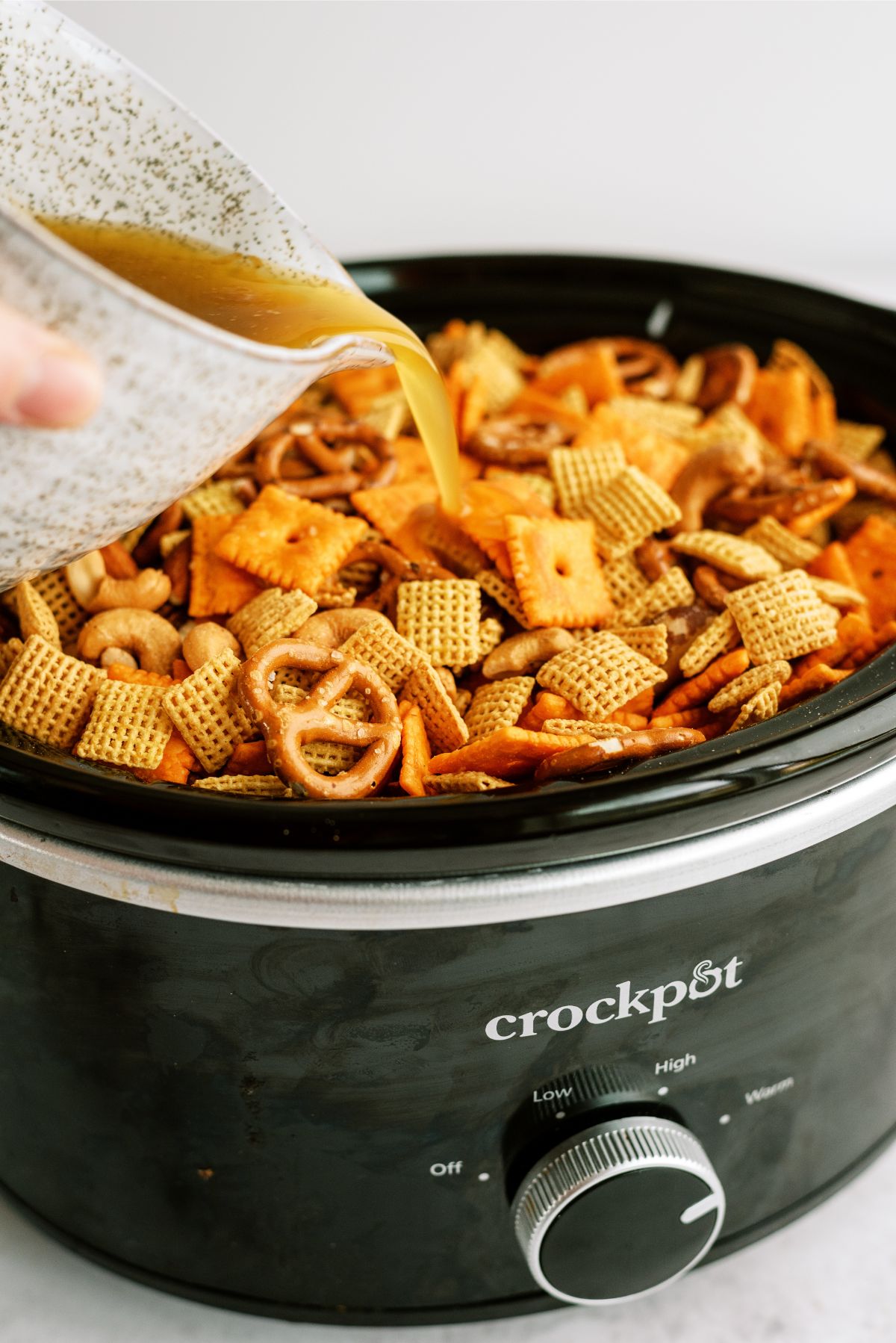 Pouring seasoning on Slow Cooker Savory Chex Mix