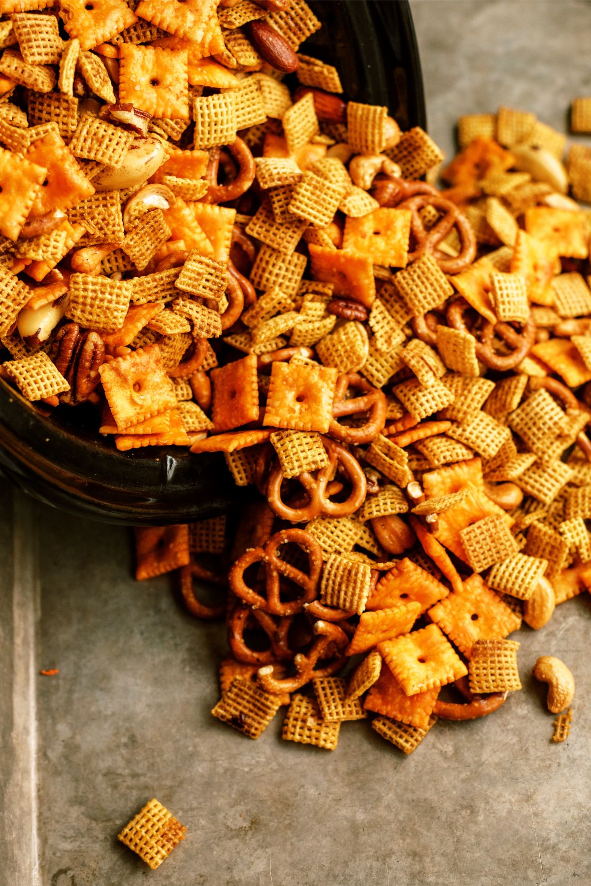 Pouring Slow Cooker Savory Chex Mix onto a sheet pan