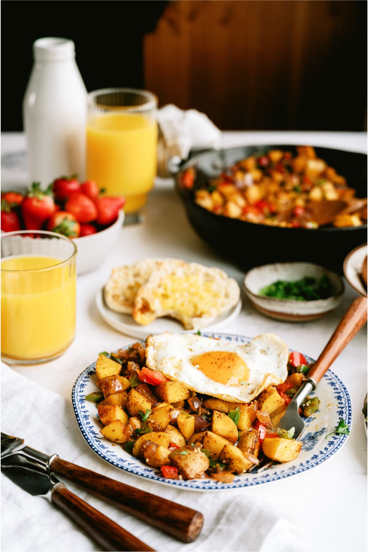Breakfast Potatoes on a plate topped with eggs, with a skillet full of Breakfast Potatoes in the background
