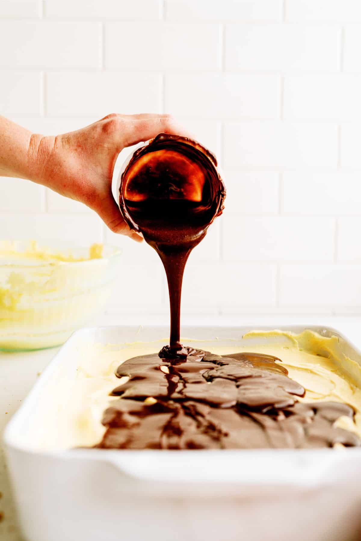 Pouring Chocolate frosting on top of pudding mixture in baking dish.