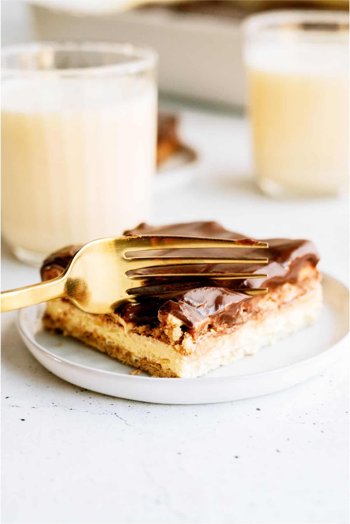 A fork slicing into a piece of Eggnog Eclair Cake on a plate.