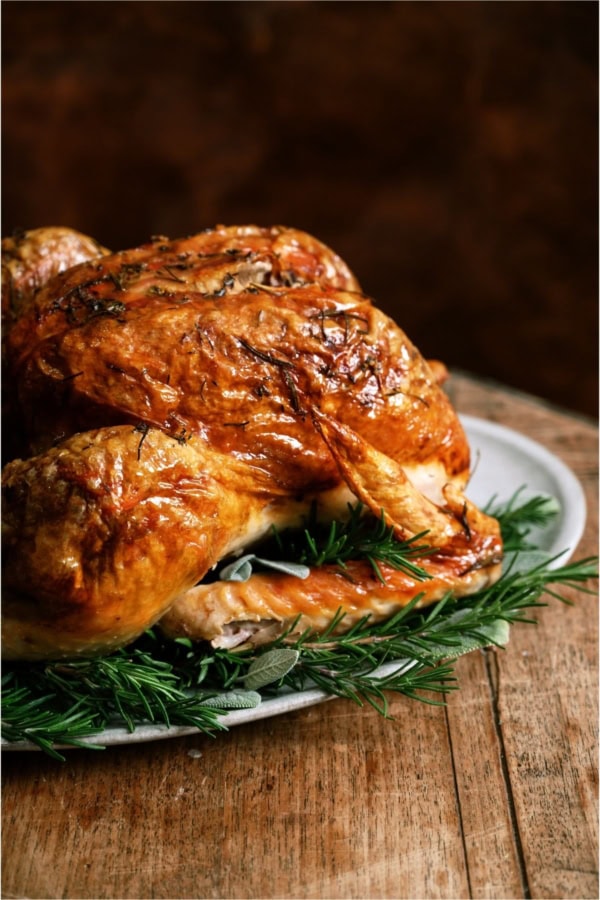 A roasted Turkey on a serving platter on top of a table.