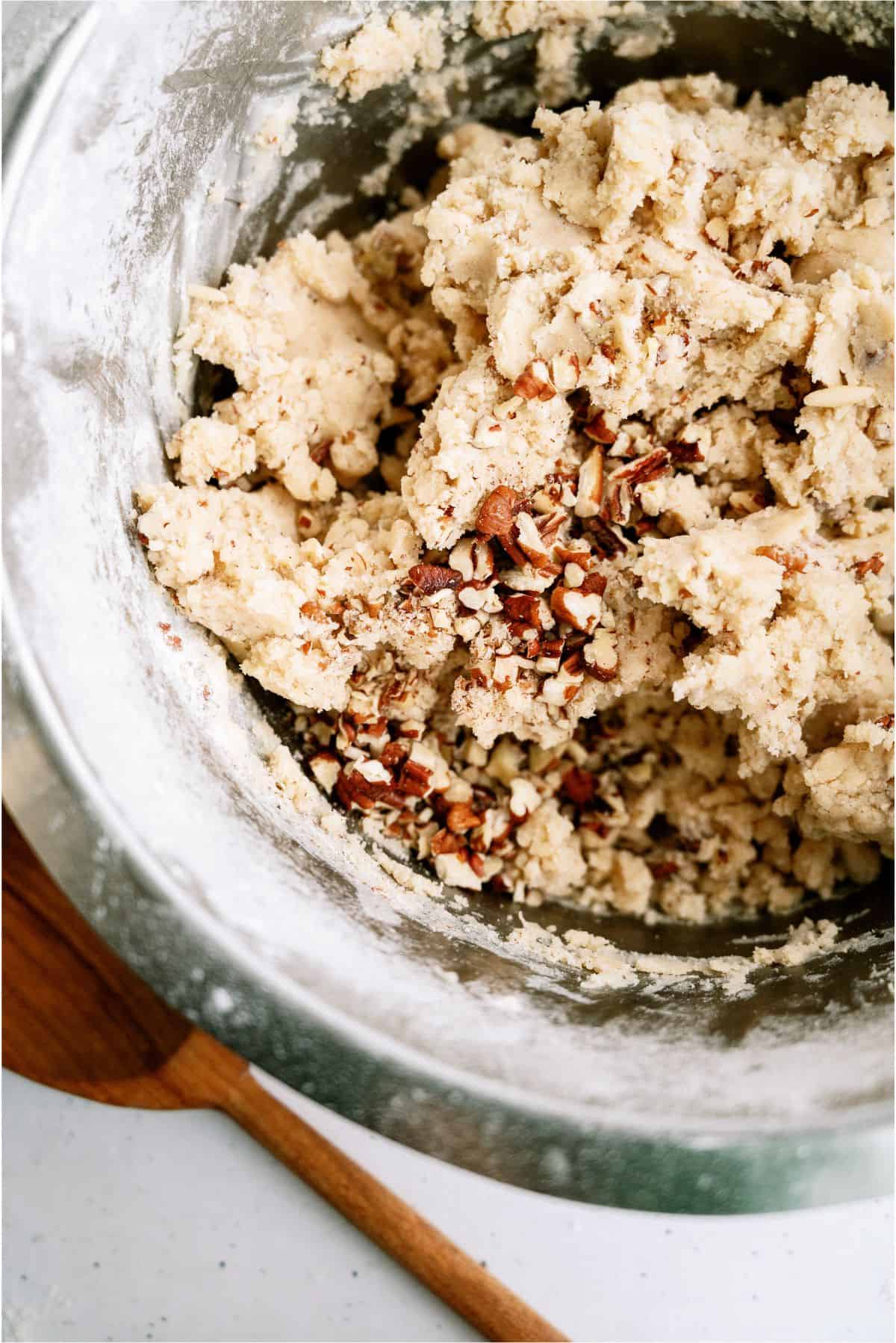 Chopped pecans added to cookie dough in mixing bowl