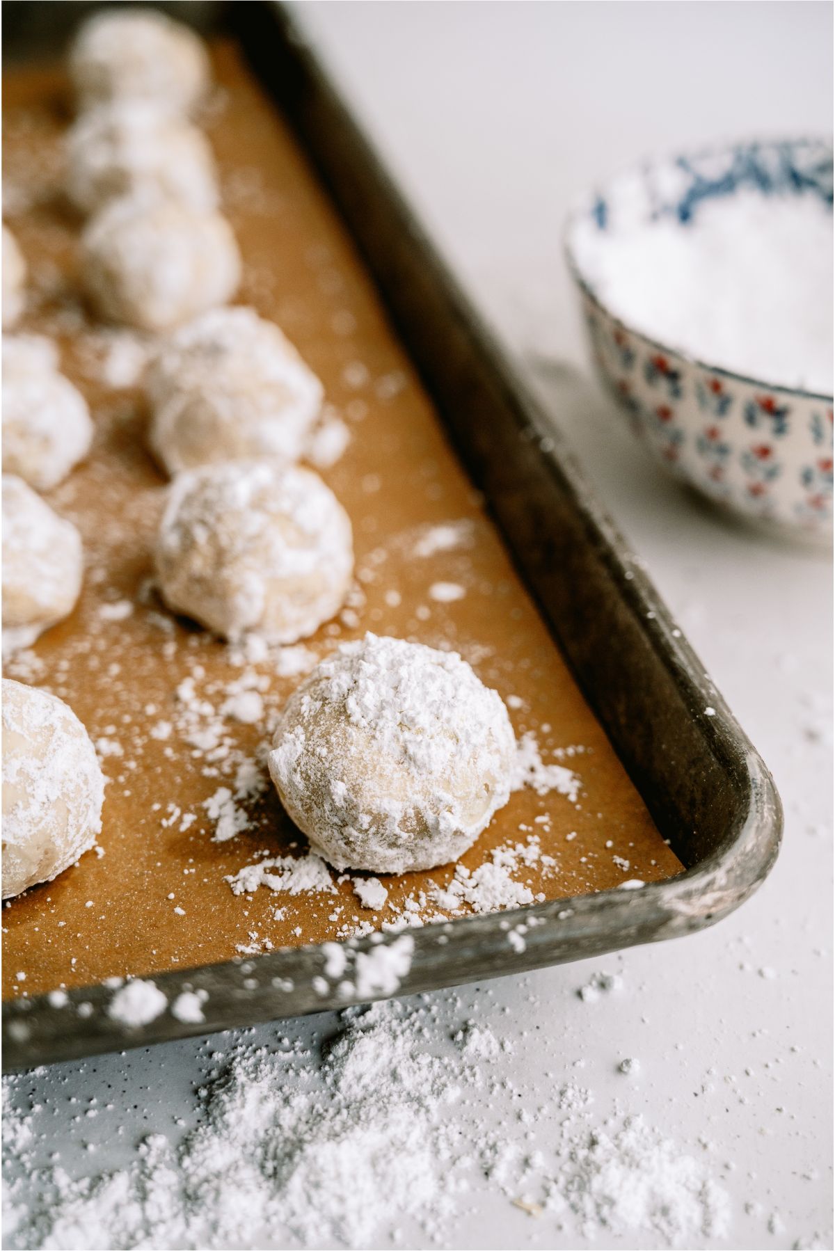 Coating baked Mexican Wedding Cookies in powdered sugar