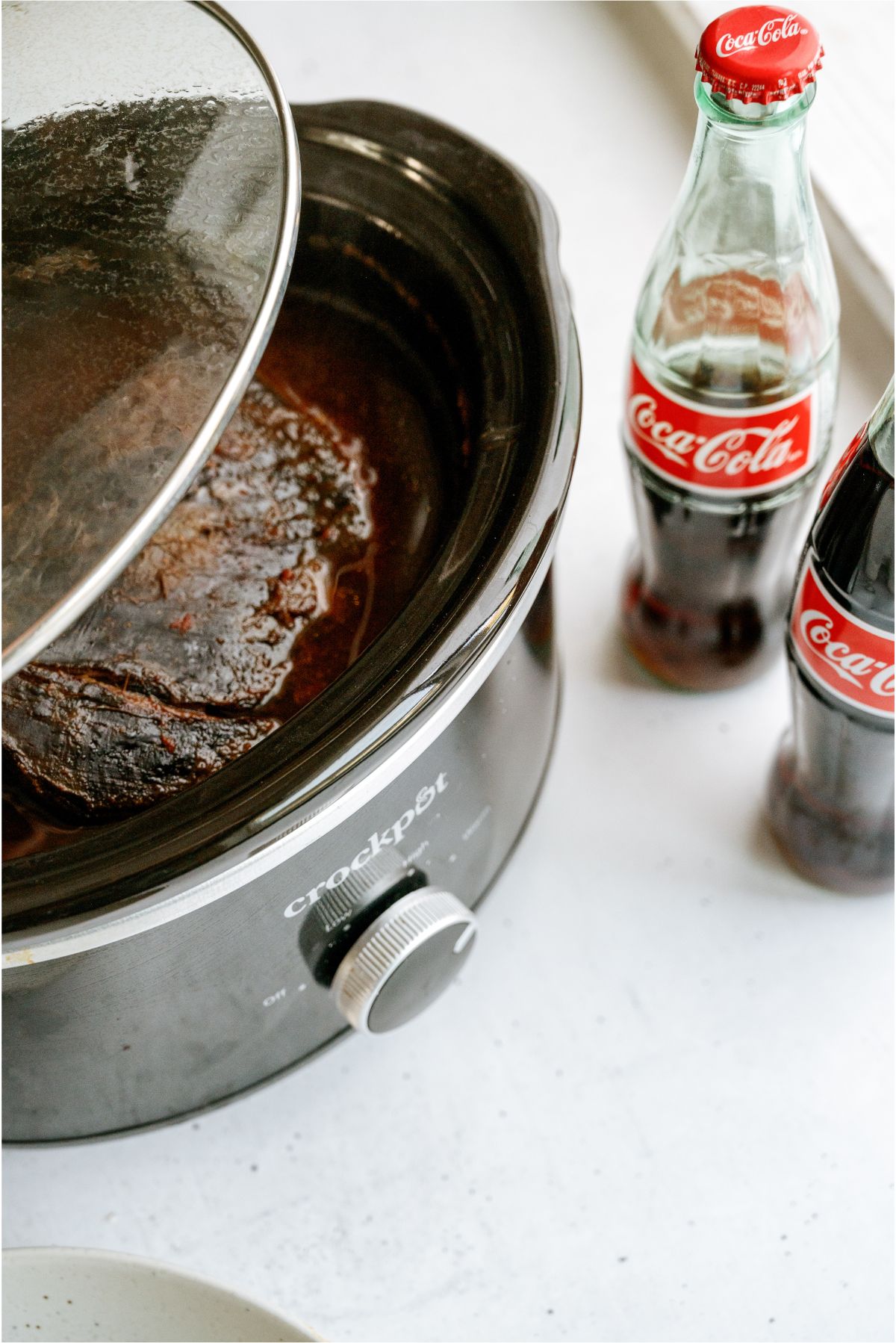 Slow Cooker Cola BBQ Roast Beef in the slow cooker with 2 bottles of coke on the side