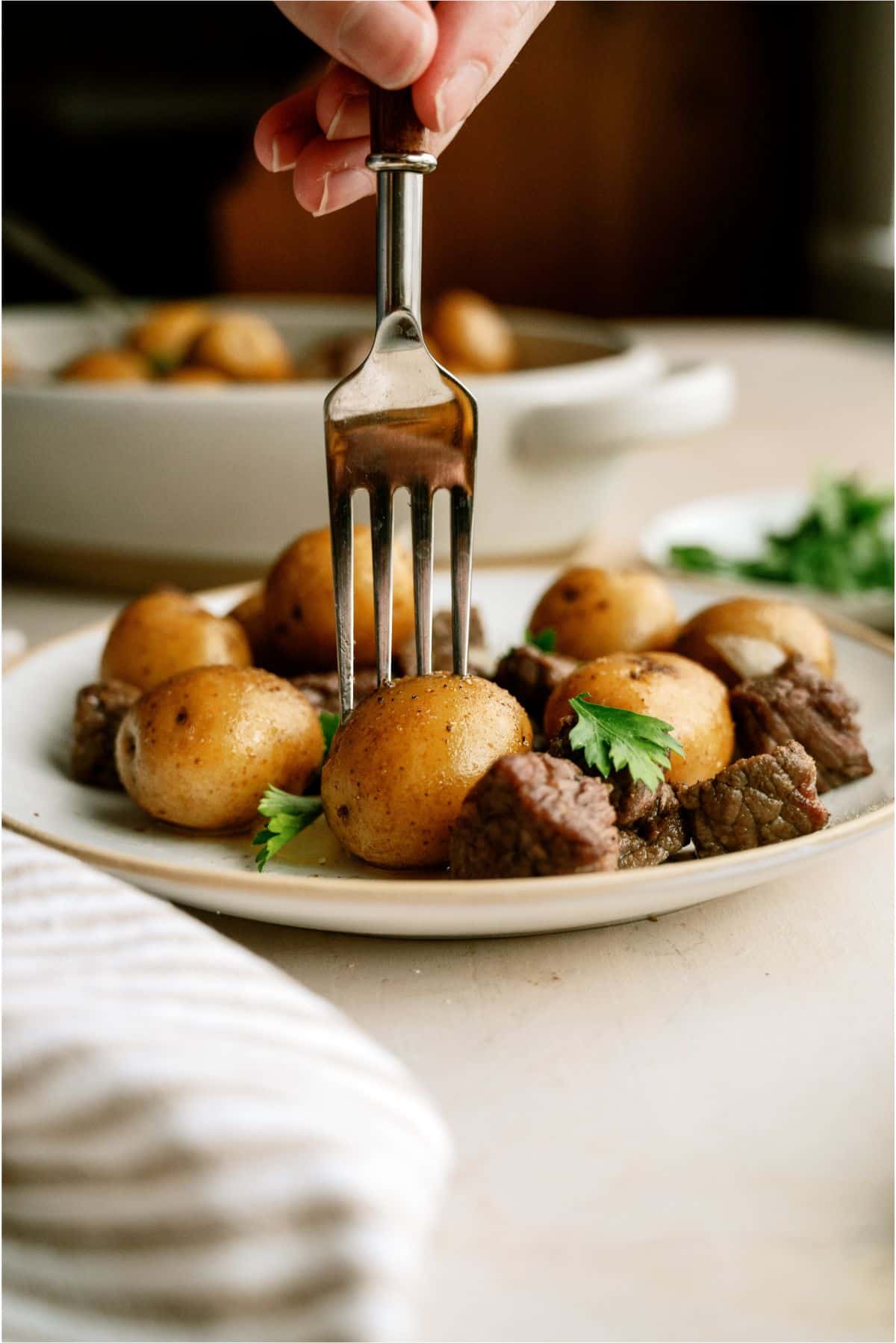 A serving of Slow Cooker Garlic Butter Steak and Potatoes on a plate with a fork