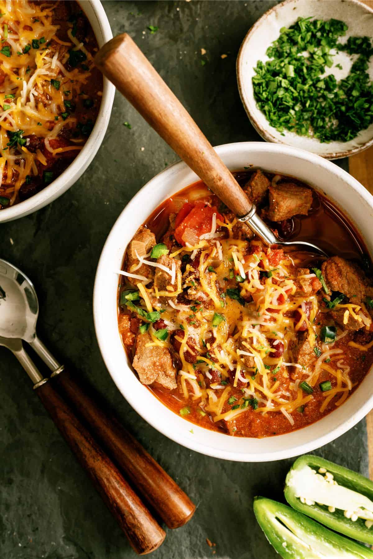 Top view of a bowl full of Texas Roadhouse Copycat Chili with toppings and a spoon