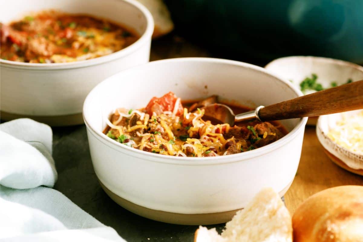 A bowl of Texas Roadhouse Copycat Chili with toppings and a spoon