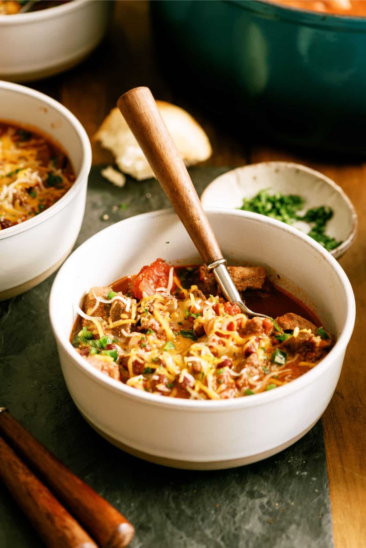 Texas Roadhouse Copycat Chili in a bowl with toppings and a spoon