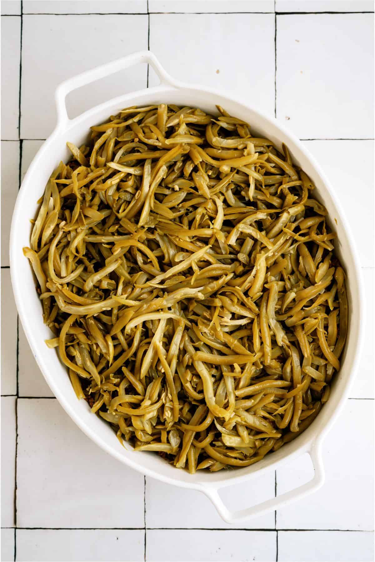 Green Beans layered on top of meat mixture in casserole dish