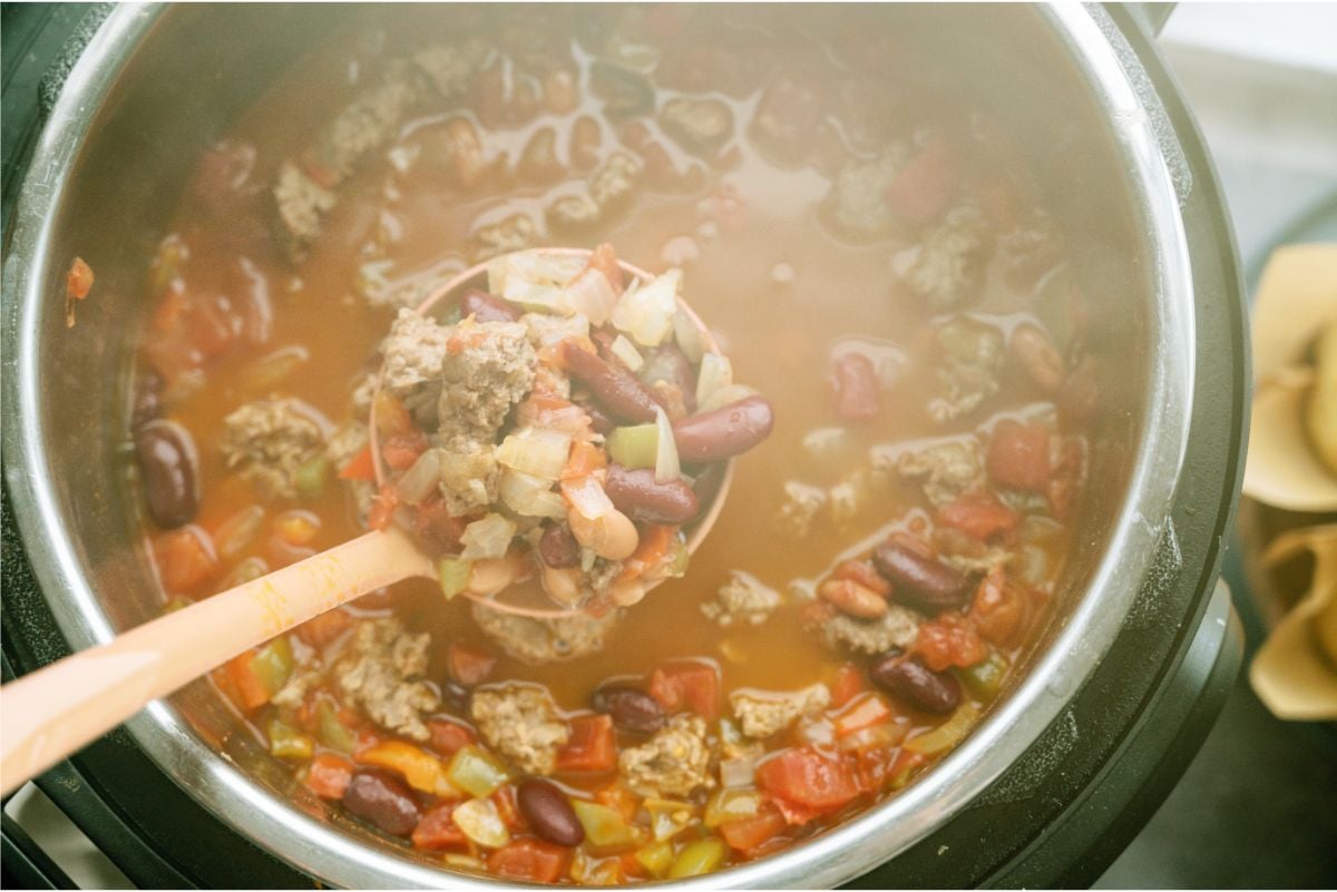 Ladle holding a scoop of Instant Pot Ground Turkey Chili over the Instant Pot