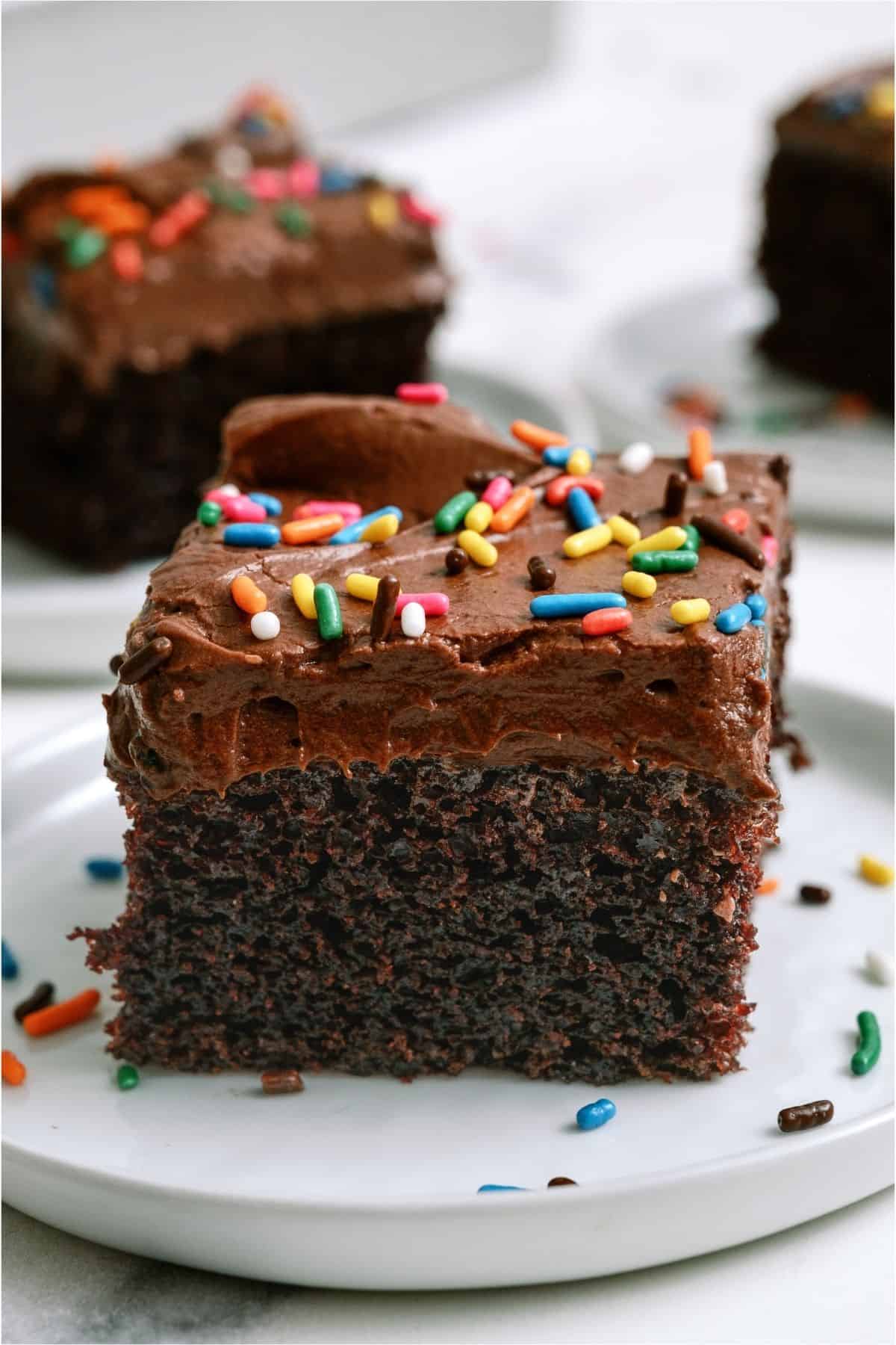 A slice of One Bowl Chocolate Cake on a white plate.