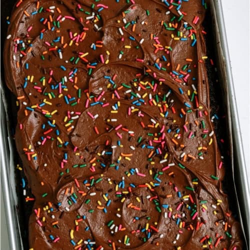 One Bowl Chocolate Cake in a cake pan on a white background.