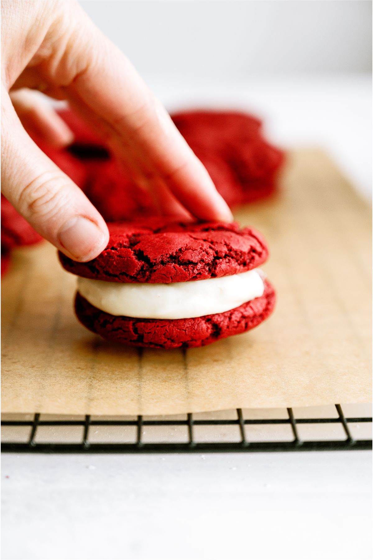 A hand holding the top of a Red Velvet Whoopie Pie Sandwich Cookies