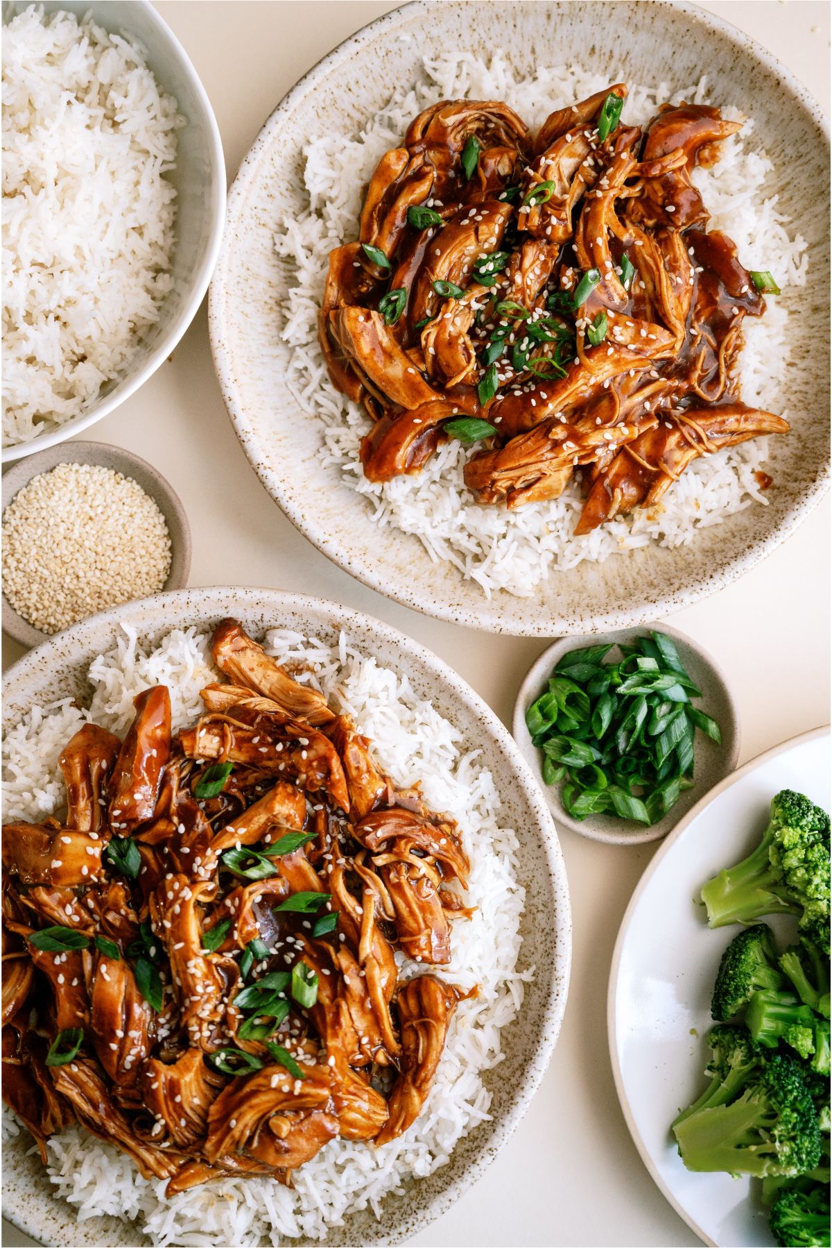 Two plates of rice topped with shredded Slow Cooker Asian Glazed Chicken