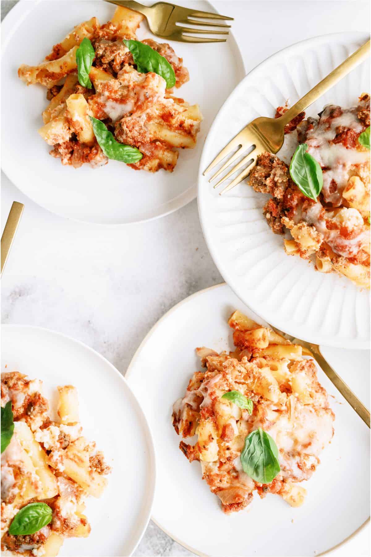 4 plates with Slow Cooker Baked Ziti on them