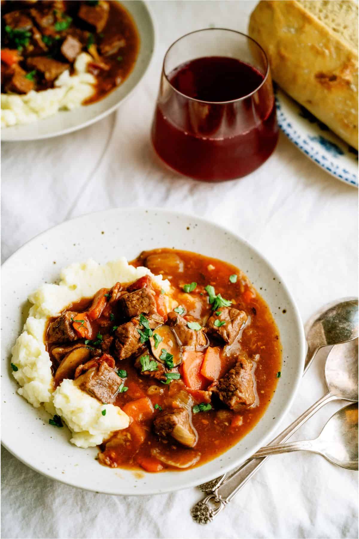 Slow Cooker Beef Bourguignon served over mashed potatoes on a plate