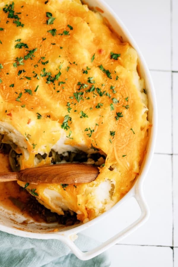 Delicious cheesy potato casserole topped with herbs in a white baking dish.