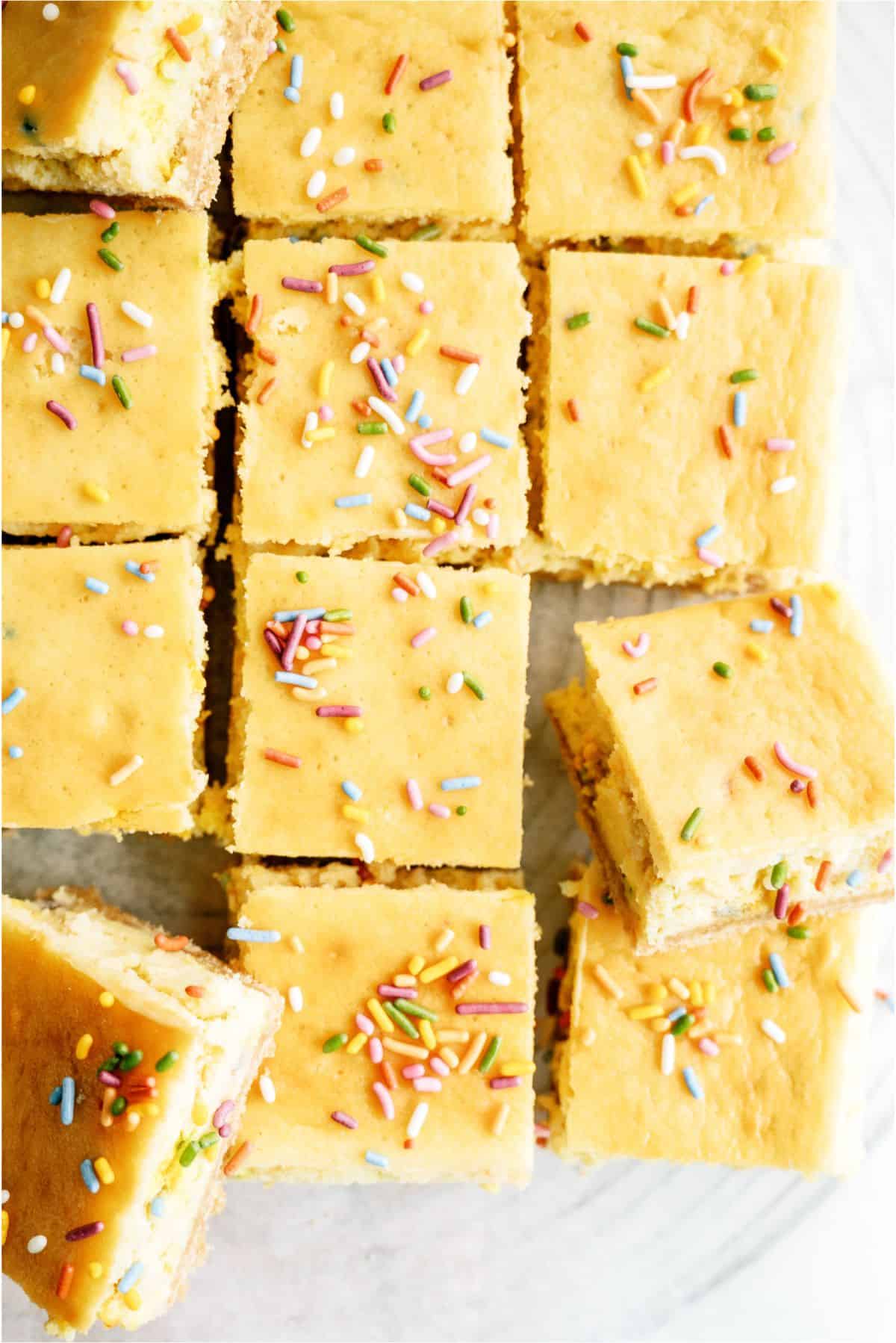 Cake Batter Cheesecake Bars cut into squares with sprinkles on top.