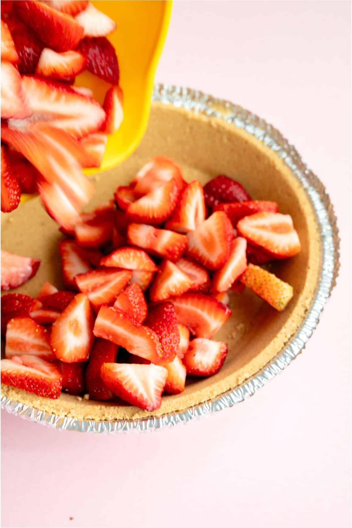 Fresh strawberries sliced and poured into pie crust.