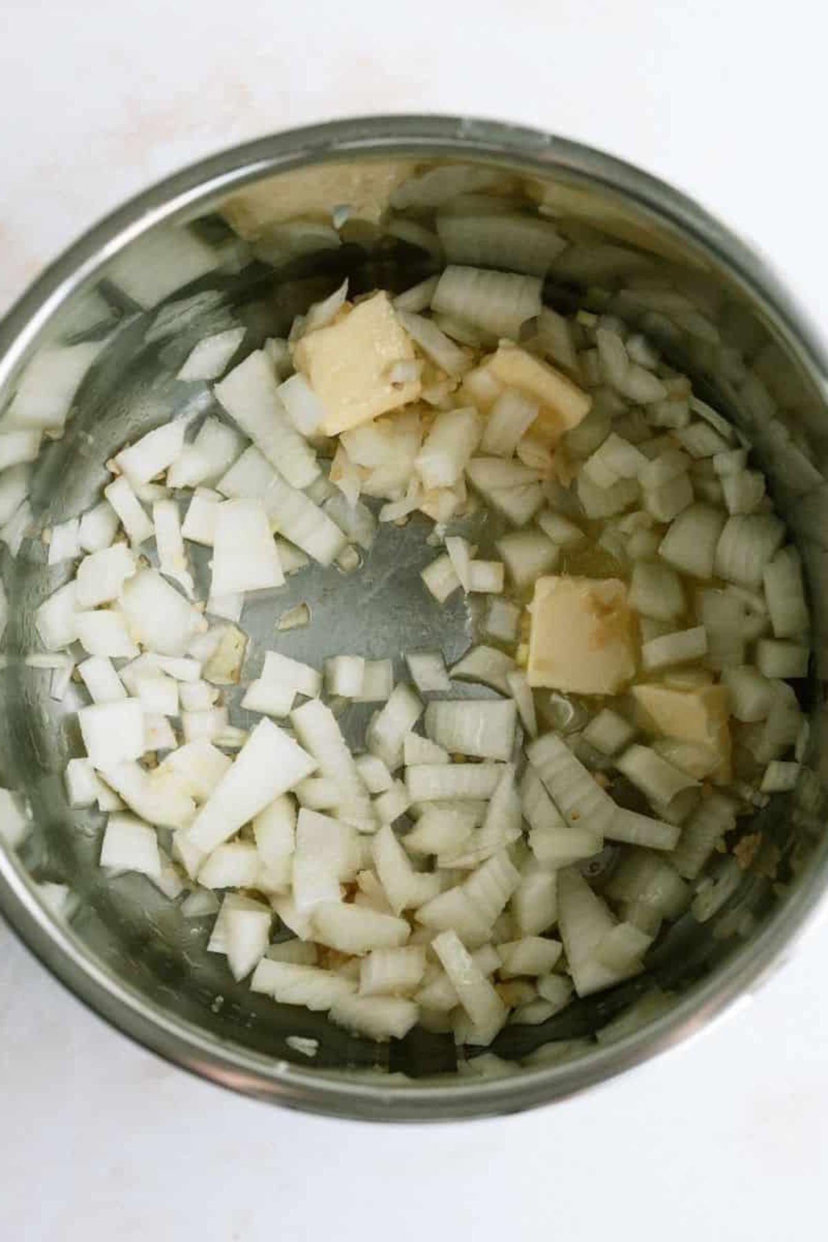 Chopped onions and sliced butter in the bottom of an Instant Pot.