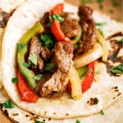 A flour tortilla filled with Sheet Pan Steak Fajitas.