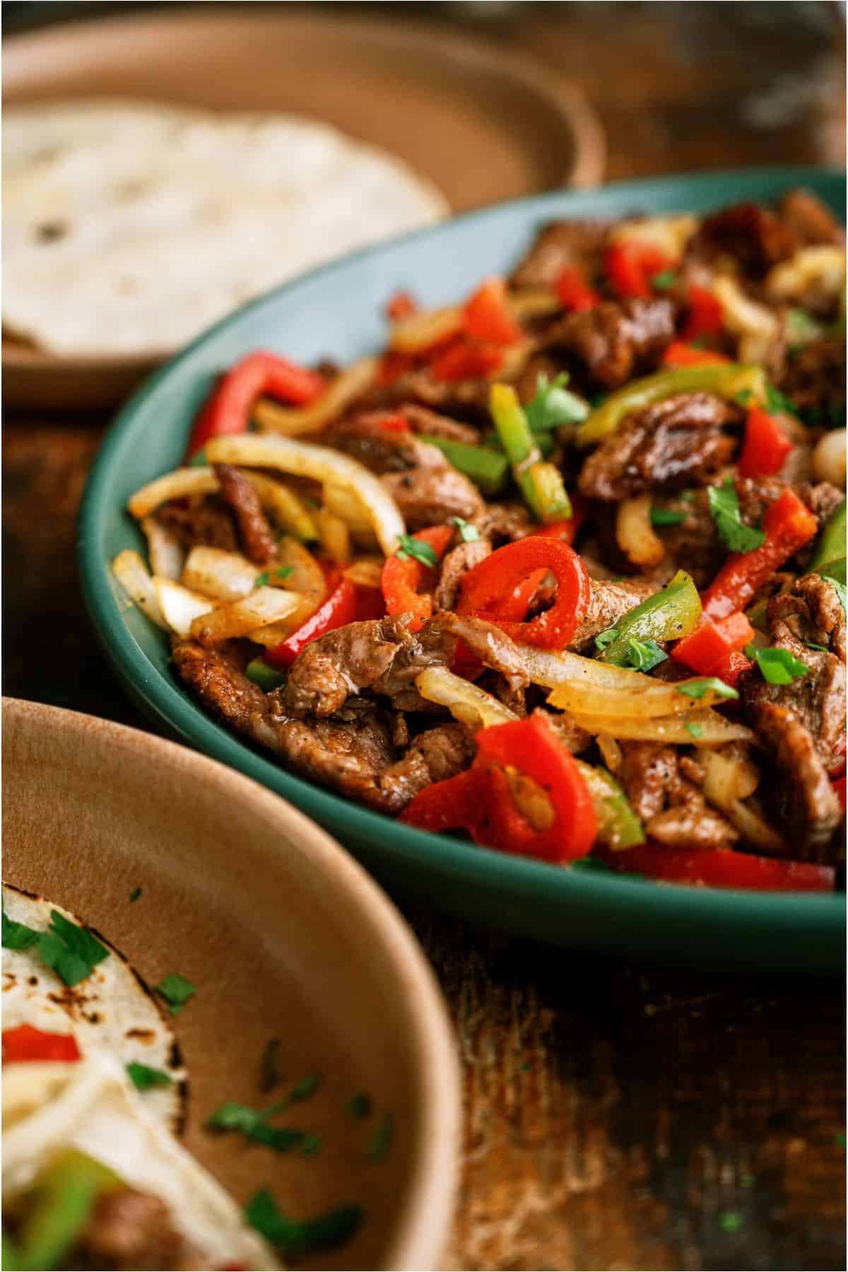 A serving bowl filled with Sheet Pan Steak Fajitas.