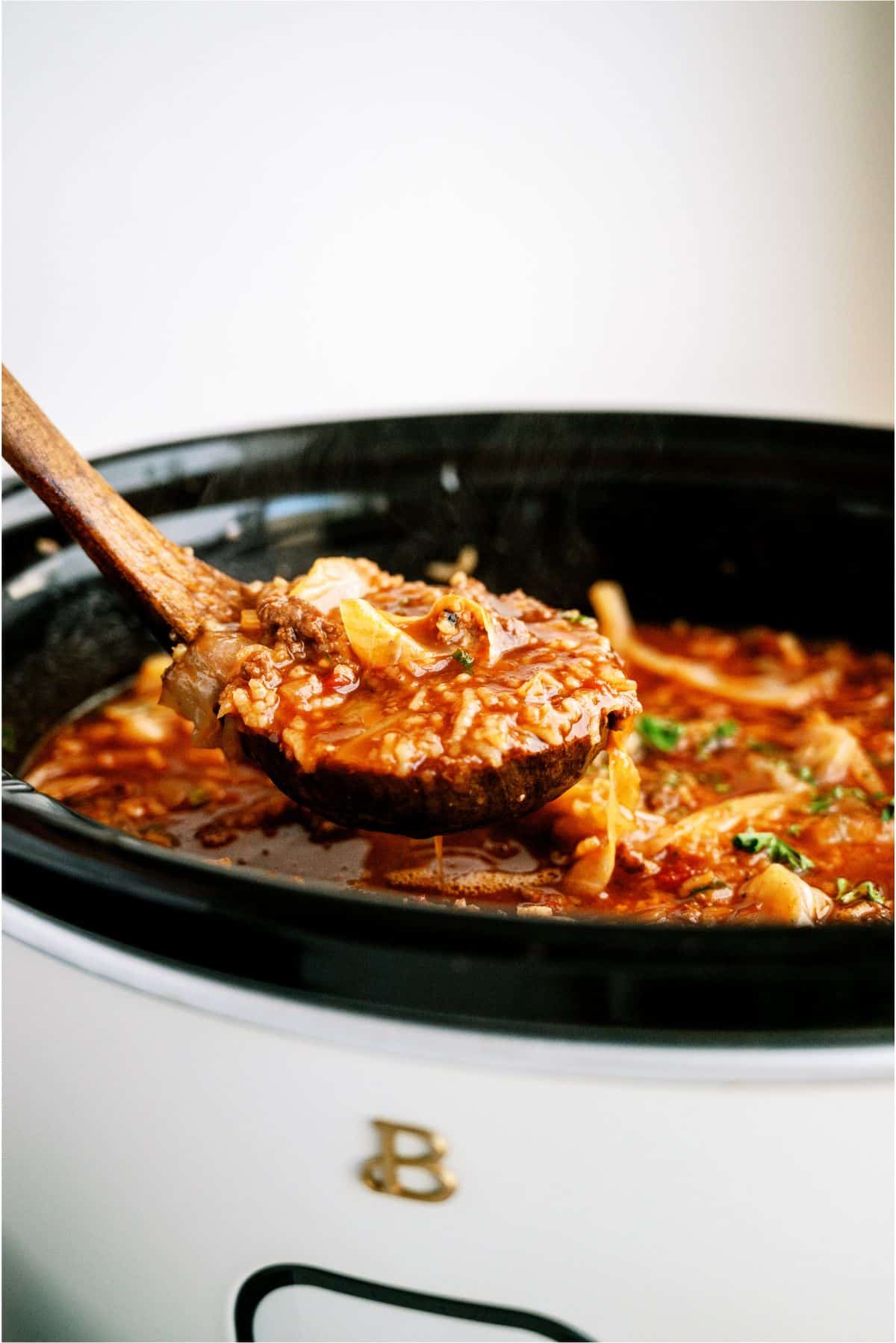 Slow Cooker Cabbage Roll Soup in the slow cooker with a wooden ladle