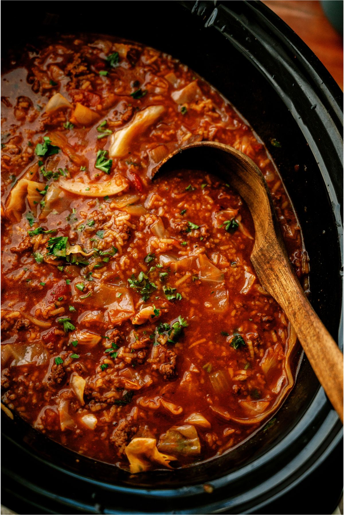 Slow Cooker Cabbage Roll Soup in the slow cooker with a wooden ladle