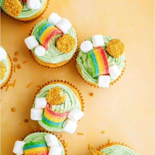 Top view of several St. Patrick's Day Cupcakes on a yellow background with gold sprinkles.