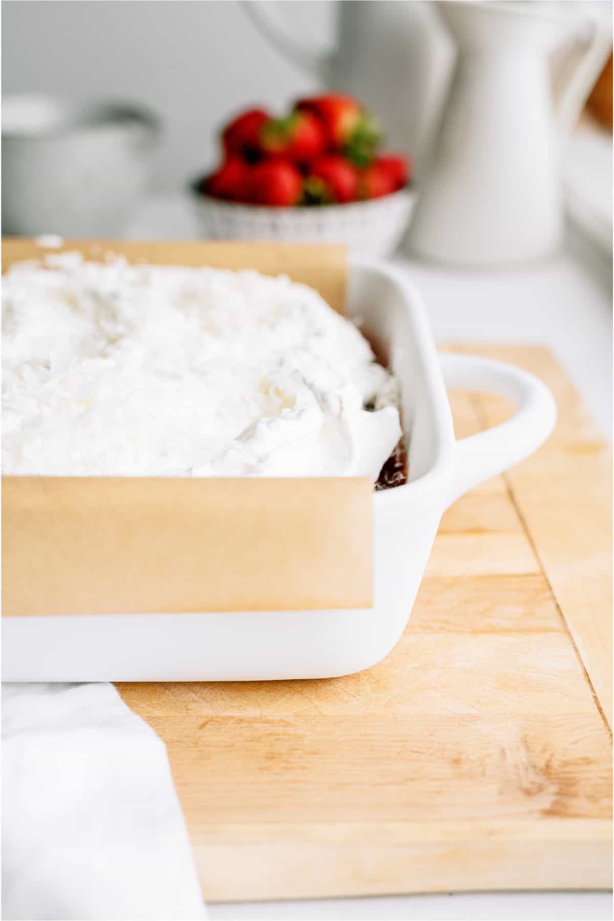 Strawberry Coconut Poke Cake topped with frosting.