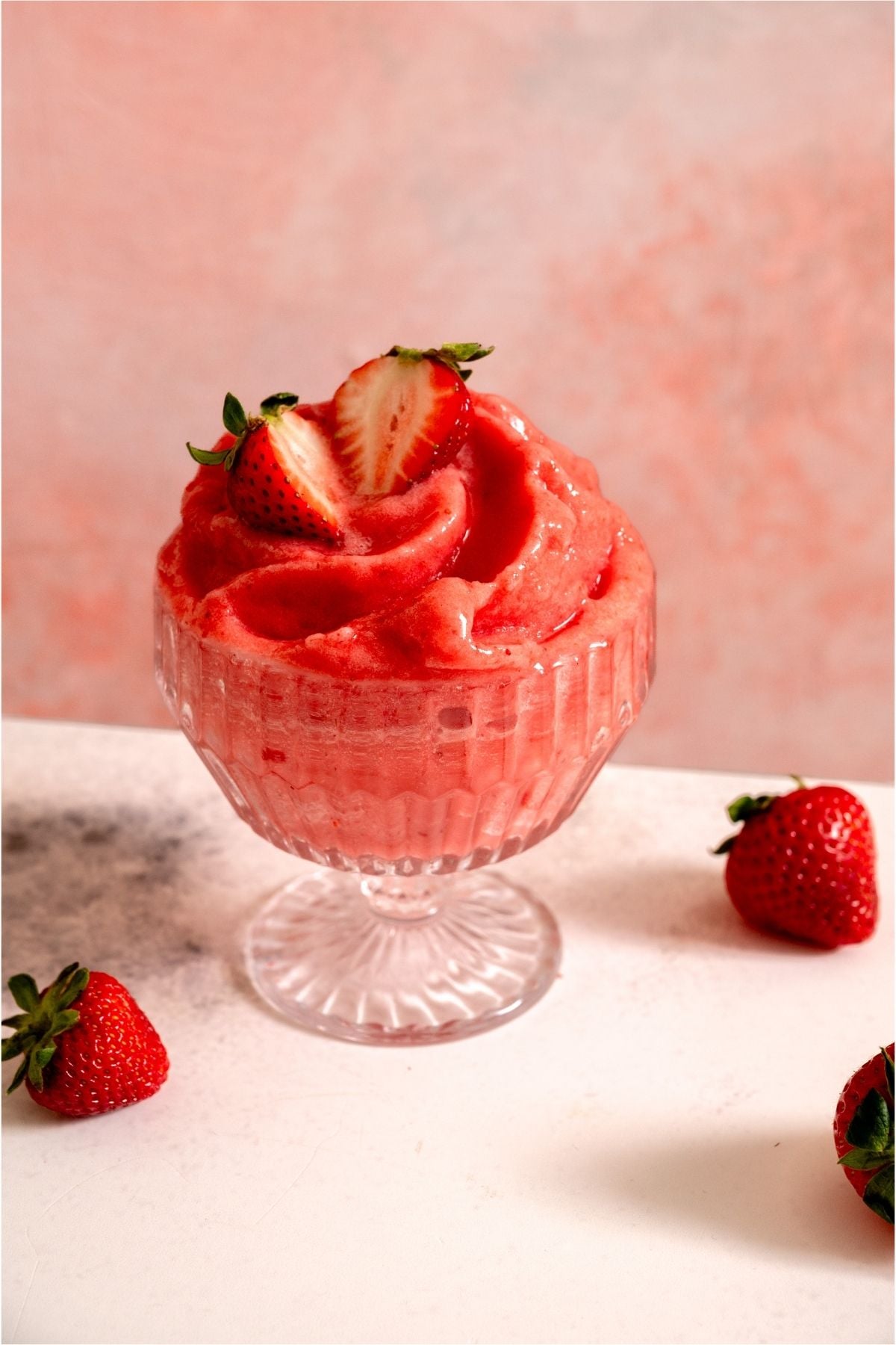 Strawberry Dole Whip in a glass surrounded by fresh strawberries.