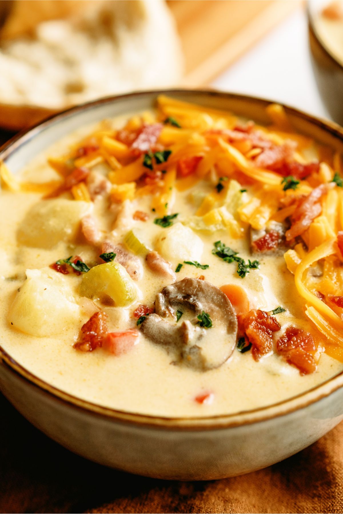Close up of a bowl of Wisconsin Bacon And Potato Cheese Soup with toppings