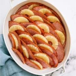 Top view of Ham and Pineapple Bake on a white background with a blue kitchen towel.