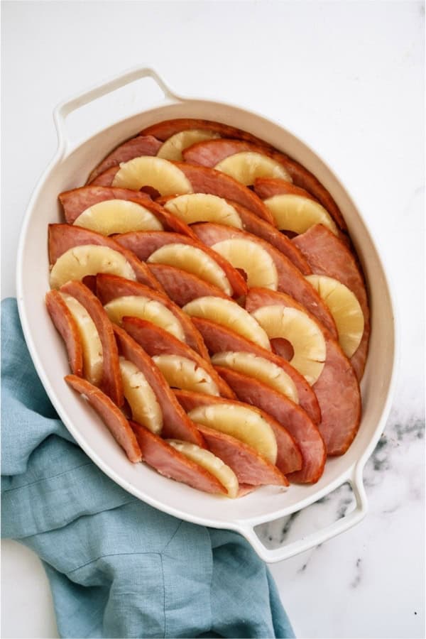 Top view of Ham and Pineapple Bake on a white background with a blue kitchen towel.