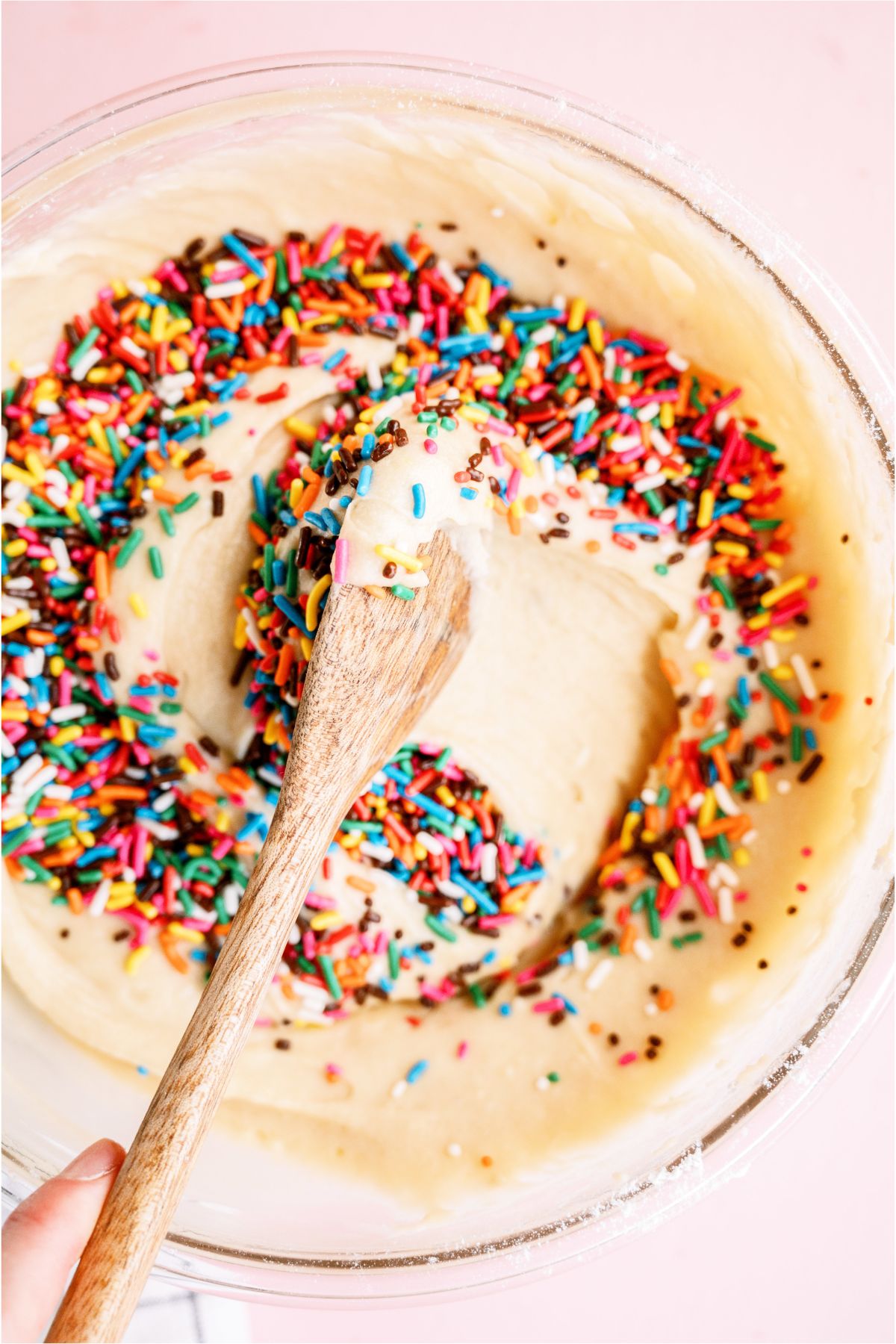 Gently mixing sprinkles into cake batter with wooden spoon